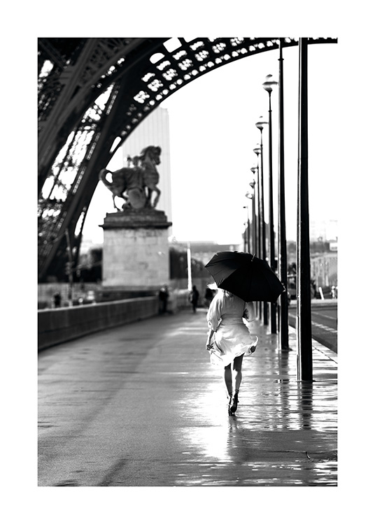  – Mustavalkoinen valokuva naisesta ja sateenvarjosta kävelyllä Eiffel-tornin alla