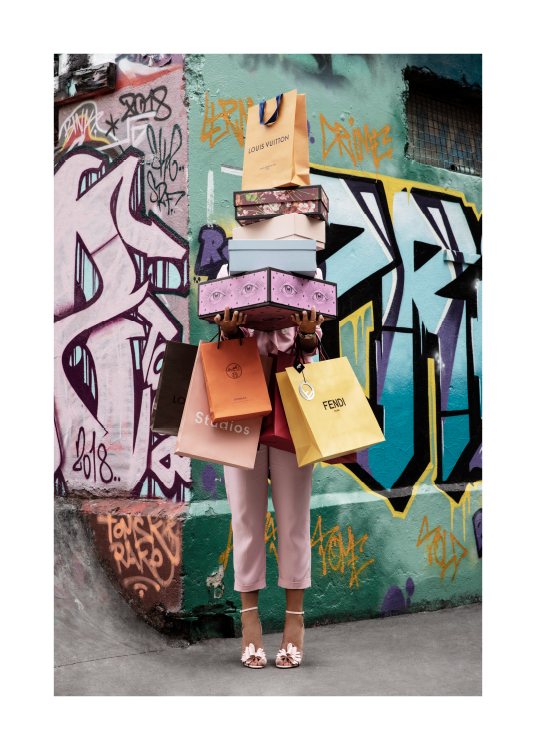  – Valokuva naisesta ostoskasseineen ja kenkälaatikoineen graffitiseinän edessä