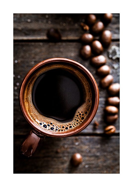  – Yläviistosta kuvattu kuva kahvikupista puisella pöydällä kahvinpapuja vierellään