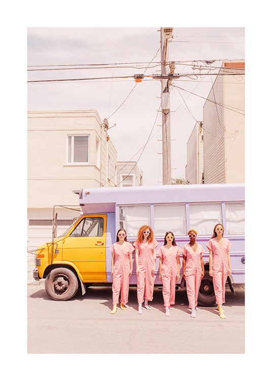  - Valokuva tytöistä vaaleanpunaisissa haalareissaan violettikeltaisen kuorma-auton edessä
