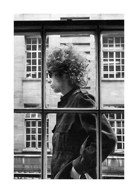  - Mustavalkoinen valokuva Bob Dylanista seisomassa ikkunan ulkopuolella