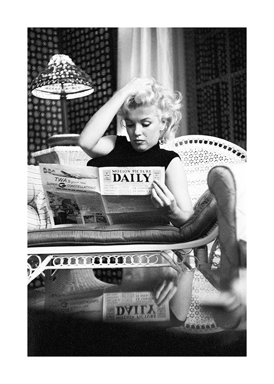  – Mustavalkoinen valokuva ikonisesta Marilyn Monroesta sohvalla lukemassa sanomalehteä