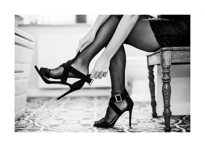  – Mustavalkoinen valokuva naisesta asettamassa korkokenkiä jalkaansa