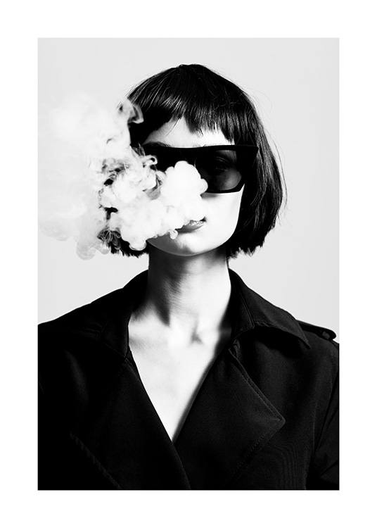  – Mustavalkoinen valokuva naisesta yllään aurinkolasit ja pikkutakki puhaltamassa savukkeen savua suustaan