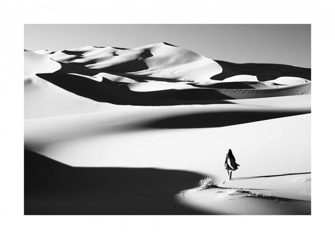  – Mustavalkoinen valokuva autiomaasta ja naisesta kävelyllä hiekkadyyneillä