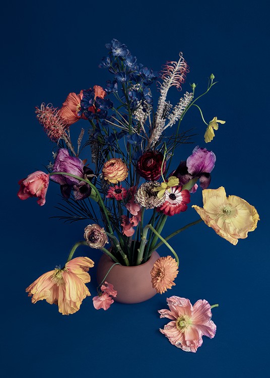  – Valokuva kirjavasta kukkakimpusta maljakossa vasten tummansinistä taustaa