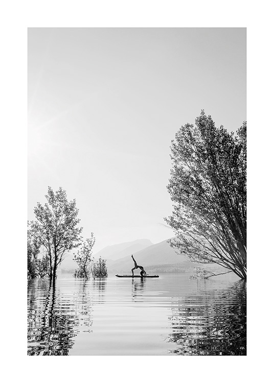  – Mustavalkoinen valokuva naisesta jooga-asennossa surffilaudalla keskellä järveä