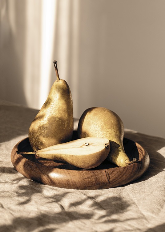  – Valokuva kolmesta päärynästä puulautasella auringossa