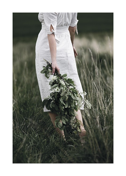  – Valokuva naisesta vihreä kukkakimppu selkänsä takana ja yllään valkoinen mekko
