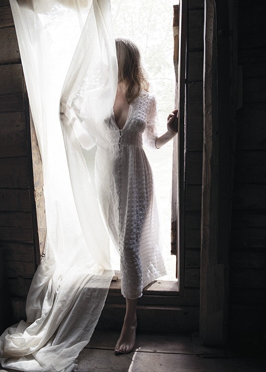  – Valokuva naisesta verhon peittämässä oviaukossa valkoisessa mekossa