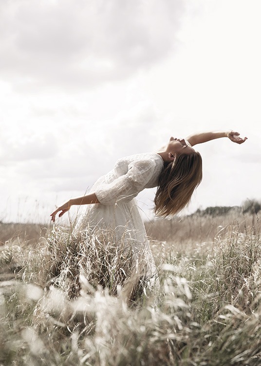  – Valokuva naisesta poseeraamassa pellolla valkoisessa mekossa