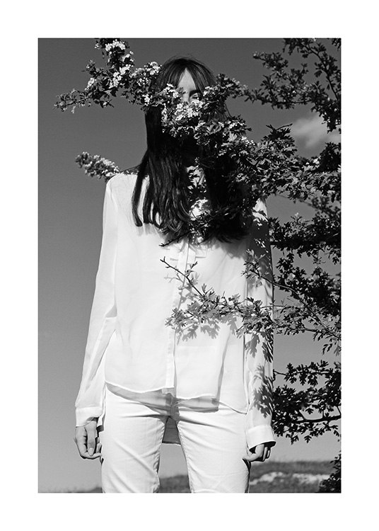  – Mustavalkoinen valokuva naisesta valkoisissa vaatteissa puunoksa edessään