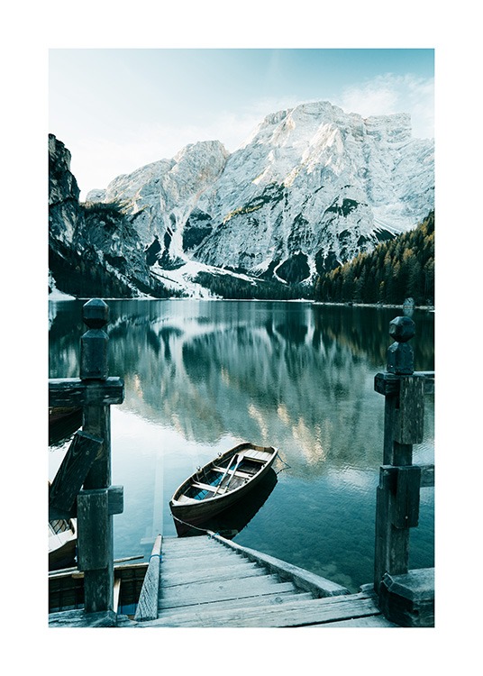  – Valokuva lumisista vuorista järven takana ja veneestä ja puuportaikosta etualalla