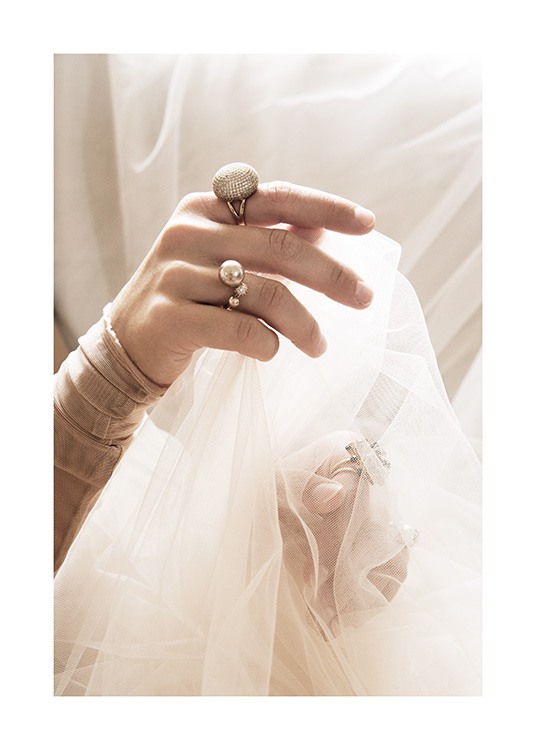  – Valokuva naisesta pitelemässä valkoista tyllikangasta käsissään sormukset sormissaan