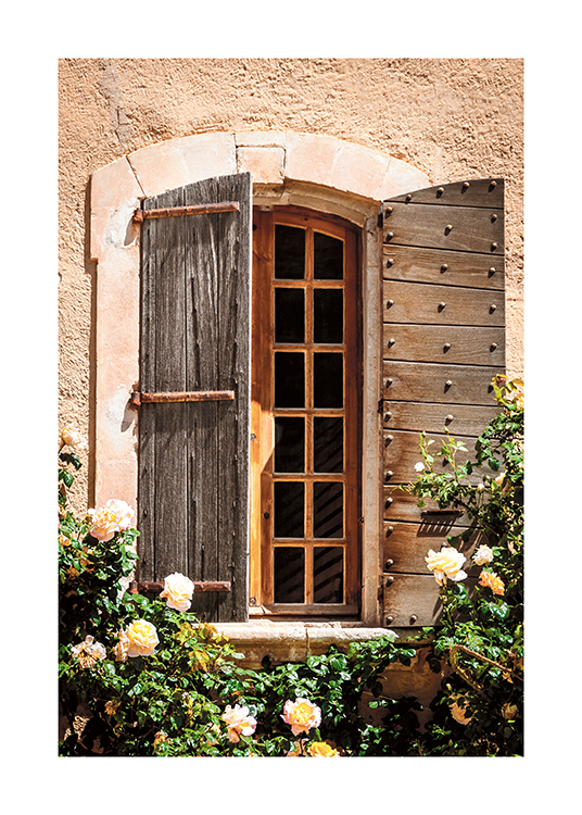  – Valokuva ruusupensaista talon edessä, jossa on puinen ikkuna
