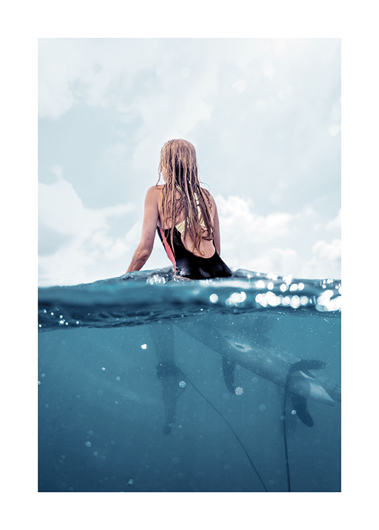  – Takaapäin otettu valokuva naisesta, joka istuu surffilaudalla meressä