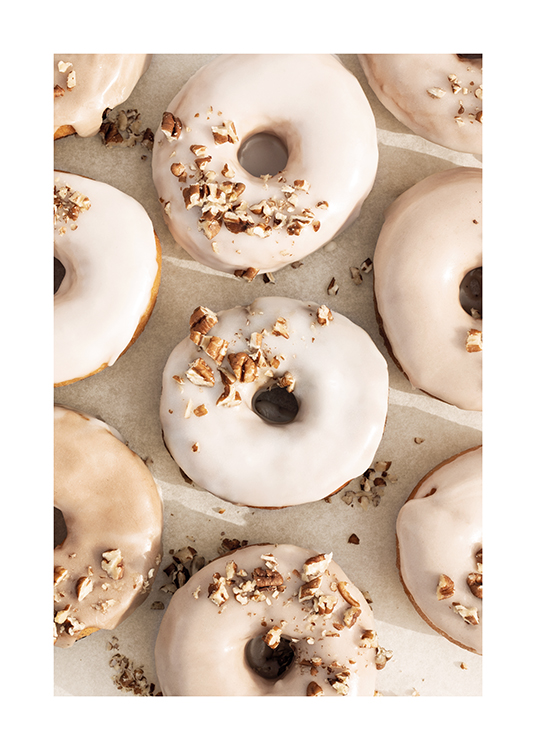  – Valokuva donitsiryhmästä beigellä ja valkoisella kuorrutuksella ja pähkinäkoristuksella