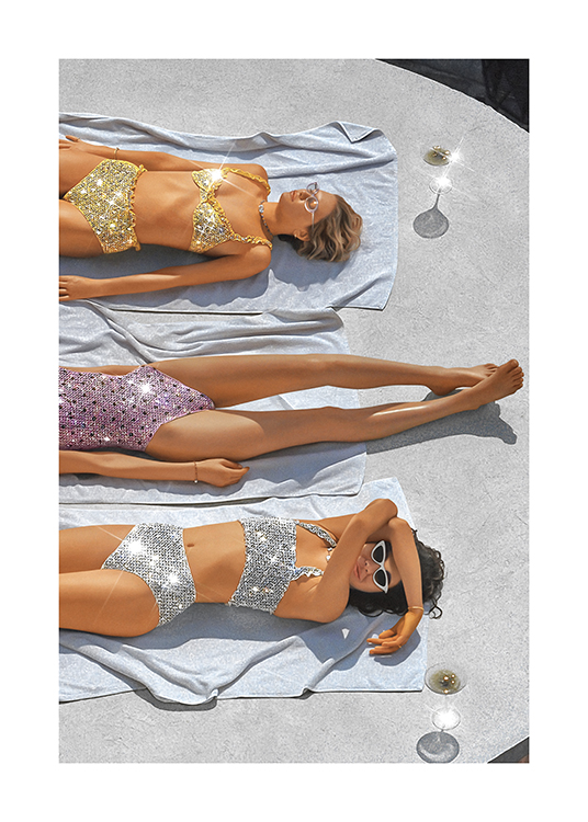  – Valokuva naisista kimaltelevissa paljettiuimapuvuissa ottamassa aurinkoa pyyhkeillä