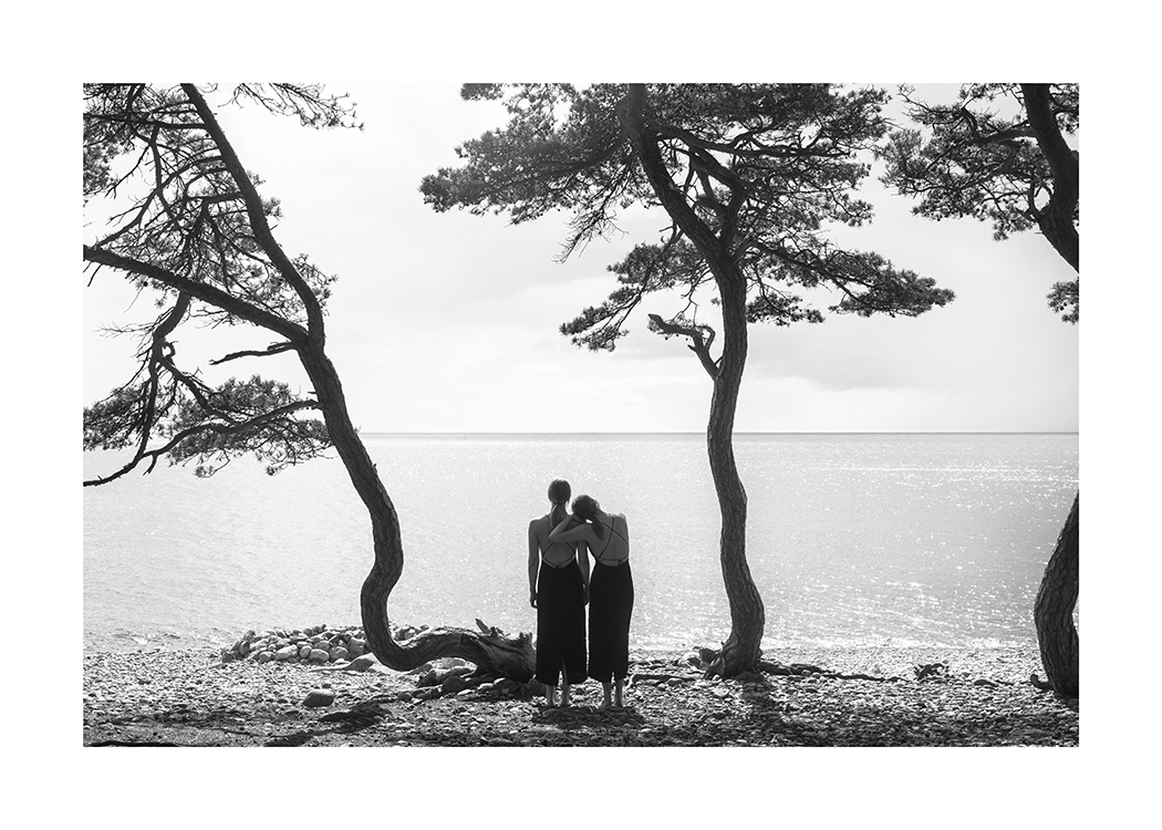  – Mustavalkoinen valokuva kahdesta naisesta, jotka katselevat vettä rannalla, jossa on puita