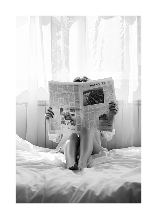 – Mustavalkoinen valokuva naisesta, joka lukee sanomalehteä sängyssä